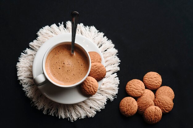 Hot coffee in a cup with some cookies on a plate. Copy space. Top view.