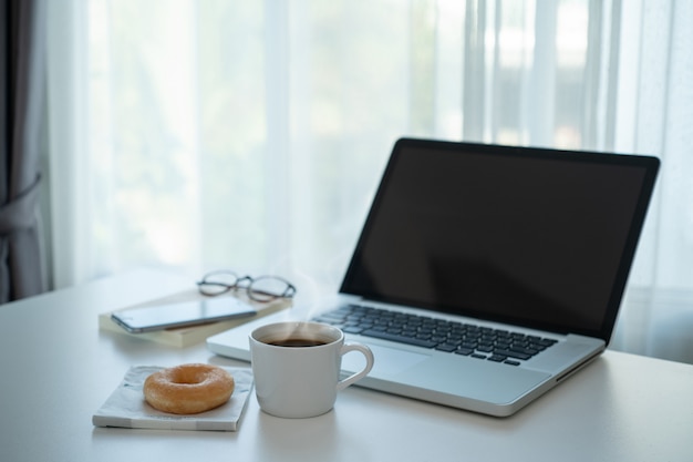 Hot coffee and donut on the table with laptop