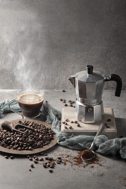 Hot coffee in a glass cup and coffee beans on a light background. Vertical format.