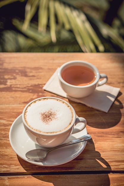 Hot coffee and hot tea place on the wooden table in early morning with copyspace