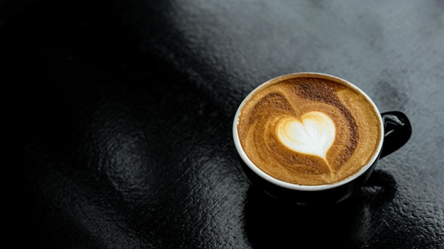 hot coffee latte art heart shape on black table