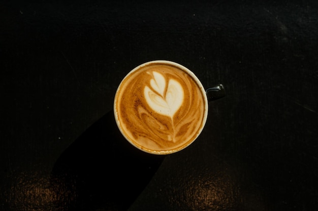 Hot coffee latte art heart shape on black table