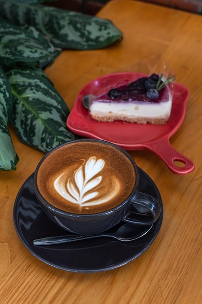 Hot coffee latte with latte art milk foam in cup and Blueberry Cake on wood desk on top view As breakfast In a coffee shop at the cafeduring business work concept