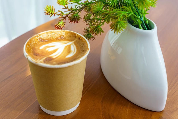 Hot coffee latte with latte art milk foam in cup made of paper on wood desk on top view As breakfast In a coffee shop at the cafeduring business work concept