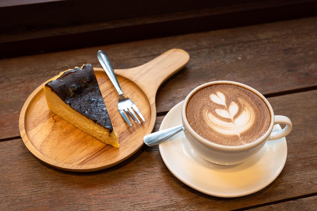 Hot coffee latte with latte art milk foam in cup mug and Homemade chocolate cake wood desk on wood desk on top view As breakfast In a coffee shop at the cafeduring business work concept