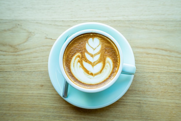 Hot coffee latte with latte art milk foam in cup mug on wood desk on top view As breakfast In a coffee shop at the cafeduring business work concept