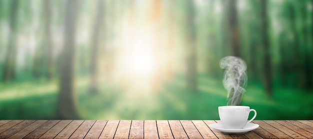 Hot coffee on the table on a spring forest background