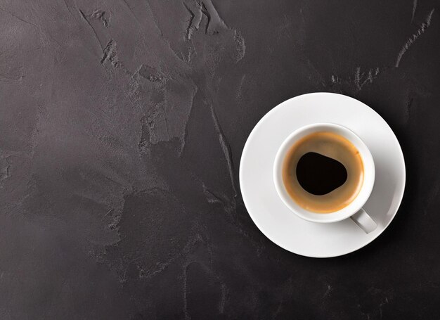 Hot coffee in a white coffee cup on dark background with copy space