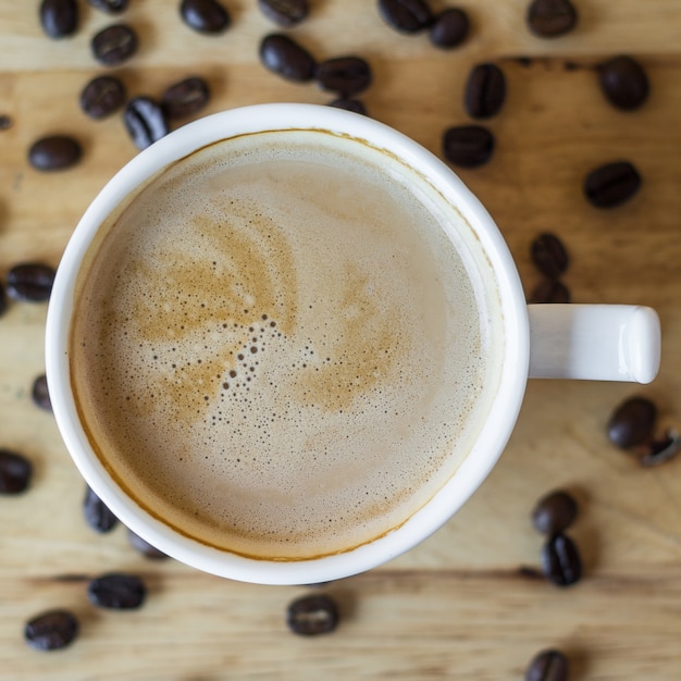 hot coffee in white cup on table with coffee beans 