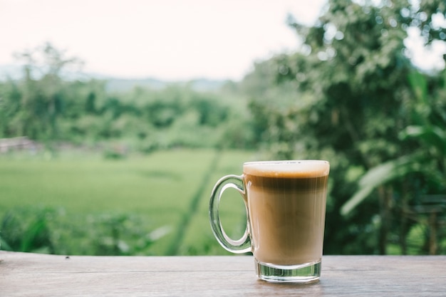 Photo hot coffee on wood table and green view background.