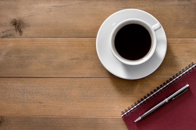 Hot cup of Americano coffee morning breakfast with red notebook and pen on classic old vintage brown