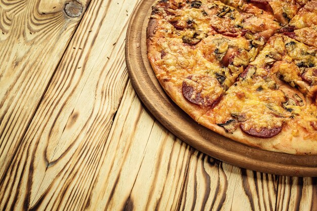 Hot delicious homemade pizza slice with melting cheese on a rustic wooden table ready for Eat