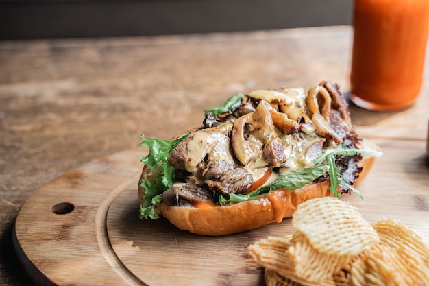 A hot dog dish with juicy beef mustard sauce on top with fried potatoes grid and a bottle of sauce