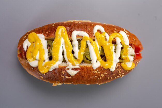 Hot dog sausage in a bun with sauces isolated on a gray background