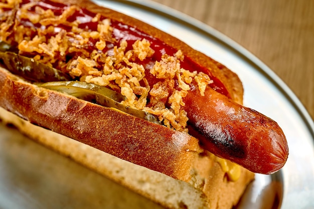 Hot dog with ketchup caramelized onions Closeup selective focus Noise added in postproduction