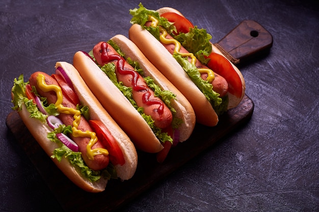 Hot dog with pickles and lettuce on blue concrete background.