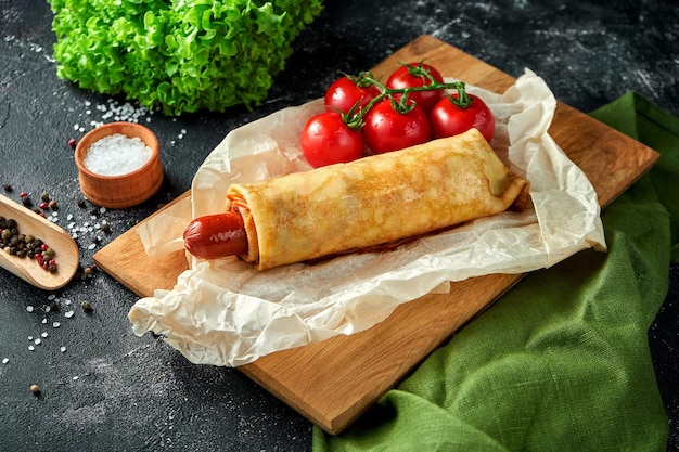 Hot dog with sauce on parchment on a dark background Sausage wrapped in crepe