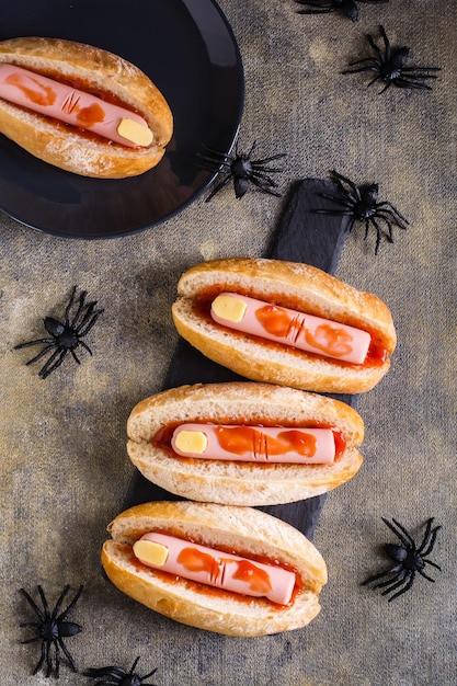 Hot dogs from sausage and cheese in ketchup in buns on slate Halloween recipe Top and vertical