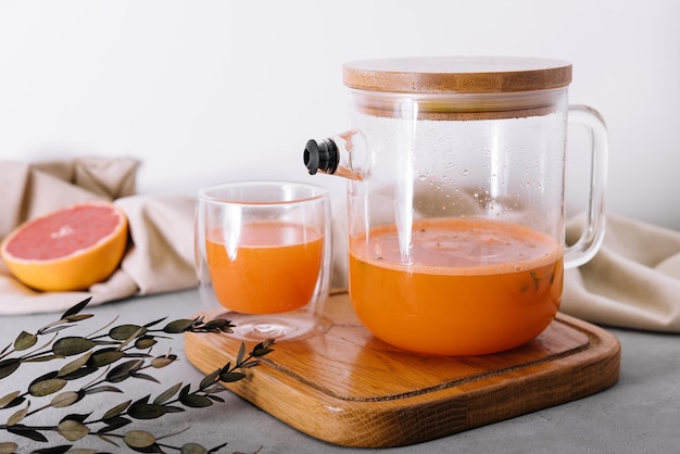 Hot drink from a seabuckthorn in a glass cup and jug