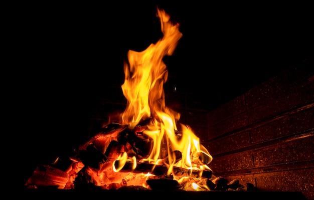 Hot fireplace full of wood. Real Flames from burning logs texture background. Fireplace background. Fire flame close up.