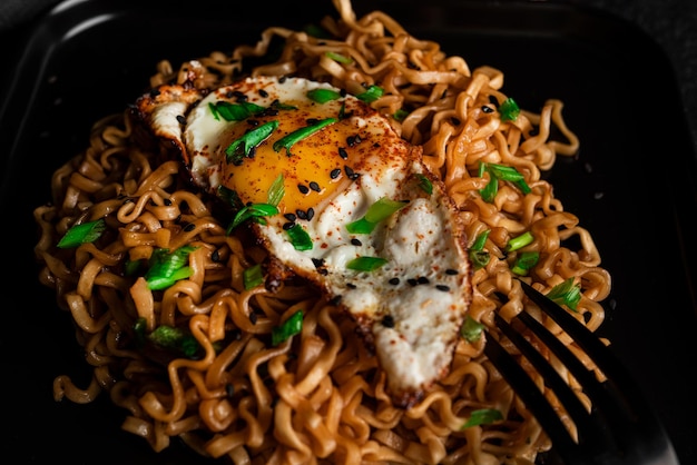 Hot fresh noodles with fried egg dark background. High quality photo