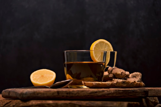 Hot gingerinfused cup on a white table with sliced ginger root in a bowl top view