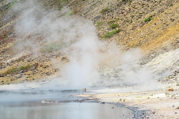 Hot hydrothermal water outlet on the shore of the lake in the caldera of the Golovnin volcano on the island of Kunashir