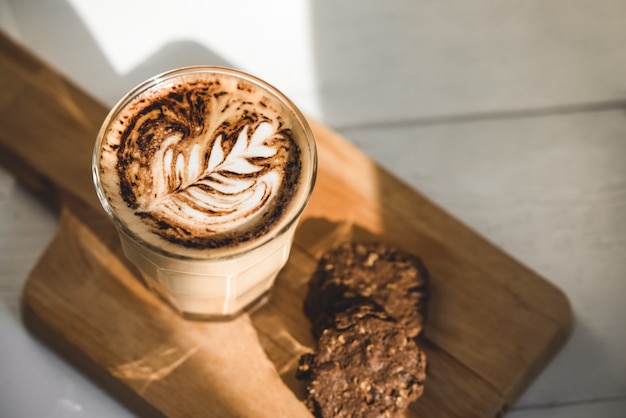 Hot latte coffee in tumbler glass with chocolate cookies