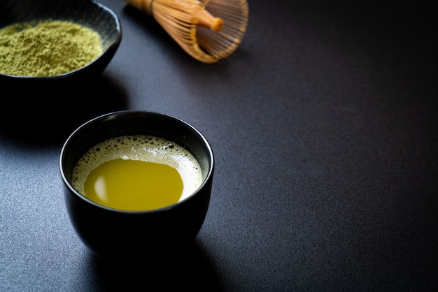 hot matcha green tea cup with green tea powder and whisk