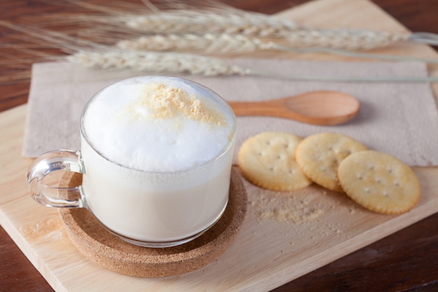 Hot milk with biscuits on wooden plate on wooden table for breakfast.