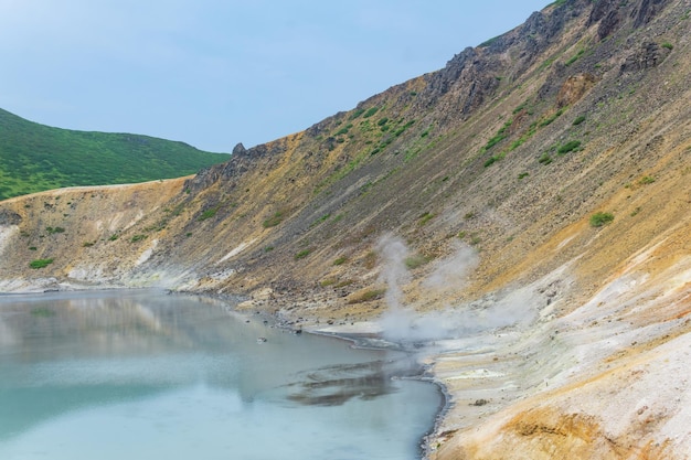 Hot mineralized lake with thermal spring and smoking fumaroles in the caldera of the Golovnin volcano on the island of Kunashir