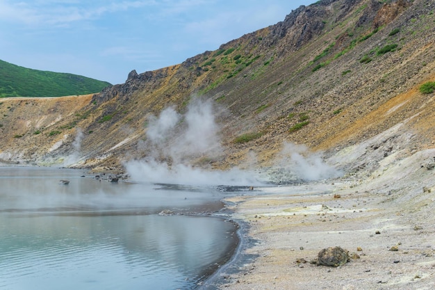 Hot mineralized lake with thermal spring and smoking fumaroles in the caldera of the Golovnin volcano on the island of Kunashir