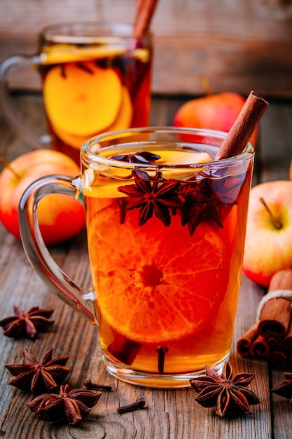 Hot mulled apple cider with cinnamon sticks cloves and anise on wooden background