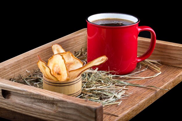 Hot mulled wine with a metal mug on a wooden board with straw and apple chips