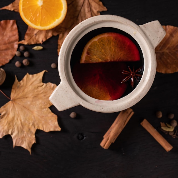 Hot mulled wine with spices and autumn leaves