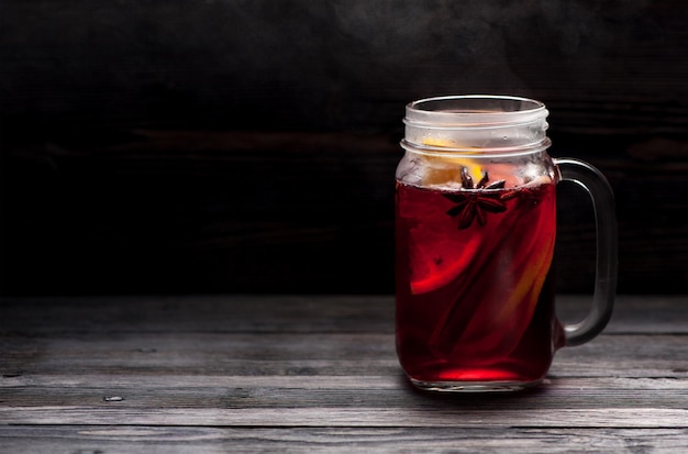 Hot mulled wine with steam in a glass jar with space for text