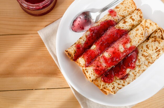 Hot pancakes in pile on a plate with a spoon poured with jam