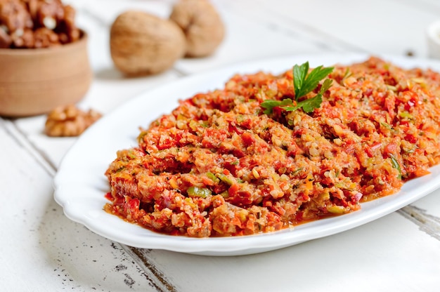 Hot pepper adjika on a plate on a white wooden background Georgian cuisine