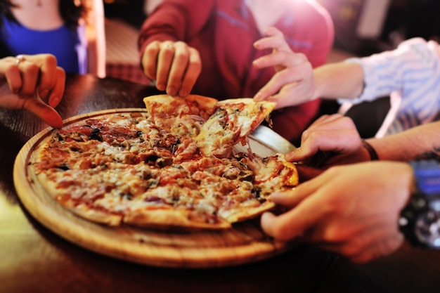 Hot pizza closeup on a table in the background of a group or company of people friends