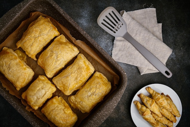 Hot puff pastry and cheese patties lie in a nonstick coated baking tray flat lay