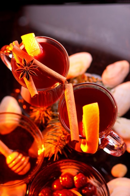 Hot red mulled wine bee honey slices of oranges and spices on a dark background Christmas decoration with spruce branches Closeup