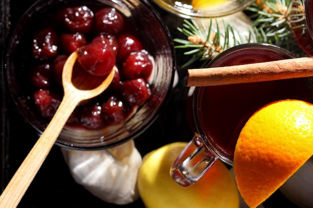 Hot red mulled wine bee honey slices of oranges and spices on a dark background Christmas decoration with spruce branches Closeup