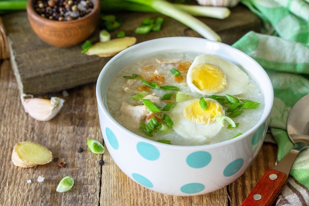 Hot soup chicken with ginger rice and garlic in a bowl on a rustic table