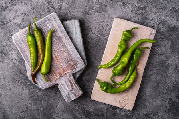 Hot spicy green chili peppers on wooden cutting boards, stone concrete