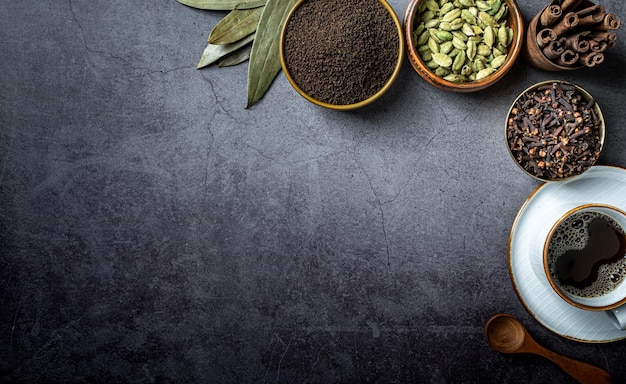 a hot tea cup with tea and raw ingredients top view on dark background