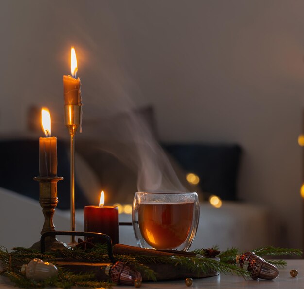 hot tea in thermo glass with christmas decor and burning candles at home