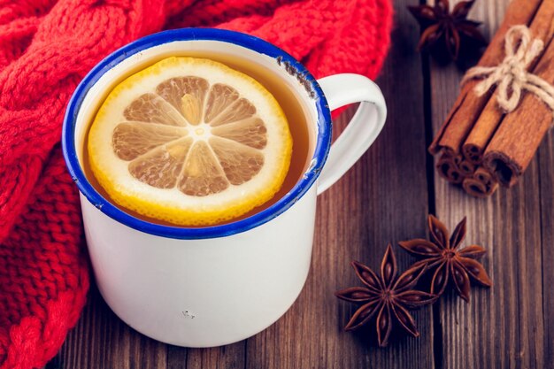 Hot tea with lemon in a rustic mug with cinnamon and anise