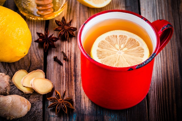 Hot tea with lemon in a rustic mug with honey ginger and anise