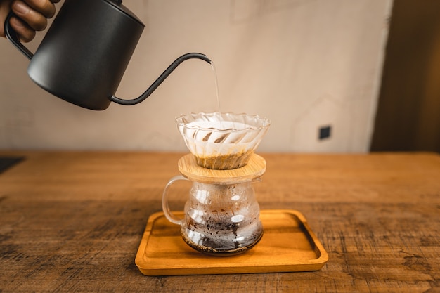 Hot water into coffee dripper above glass jar.