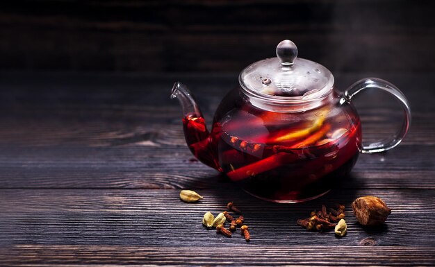 Hot wine mulled wine with spices in a glass teapot on a wooden table and space for text. Winter CHRISTMAS HOT DRINK